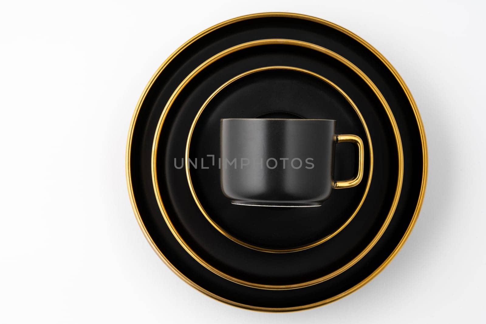 A set of black and golden ceramic plates and cup on a white background. Top view by A_Karim