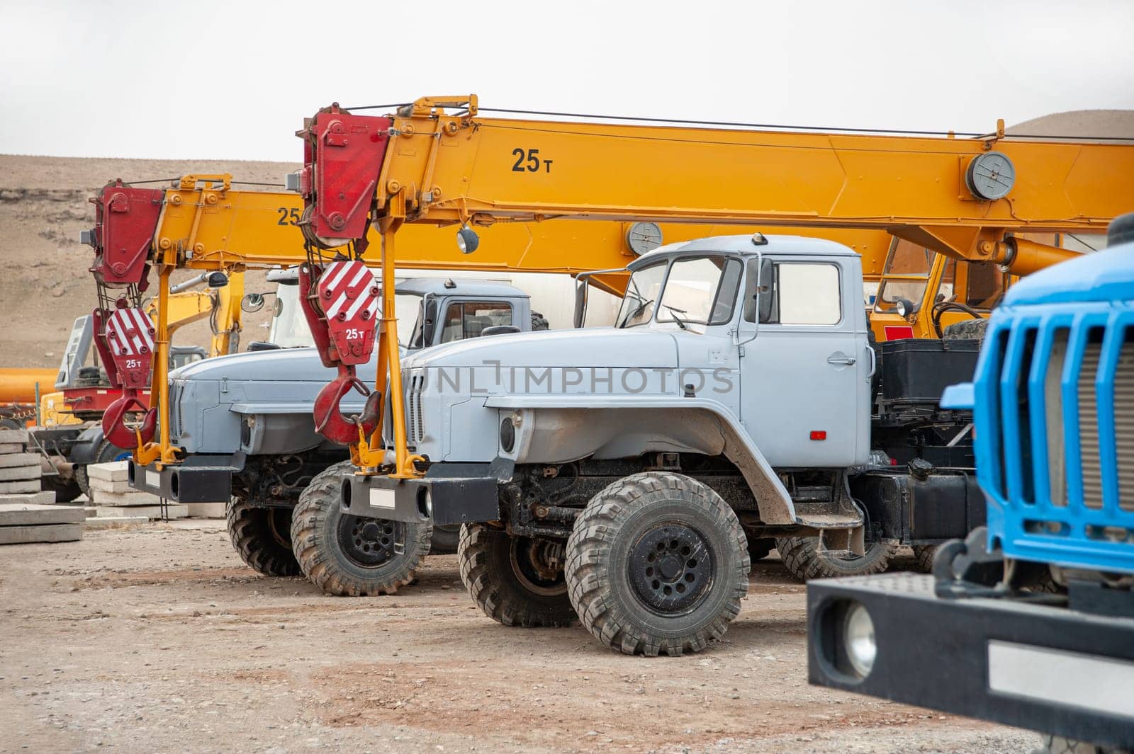 A row of large truck cranes and machines at an industrial construction site