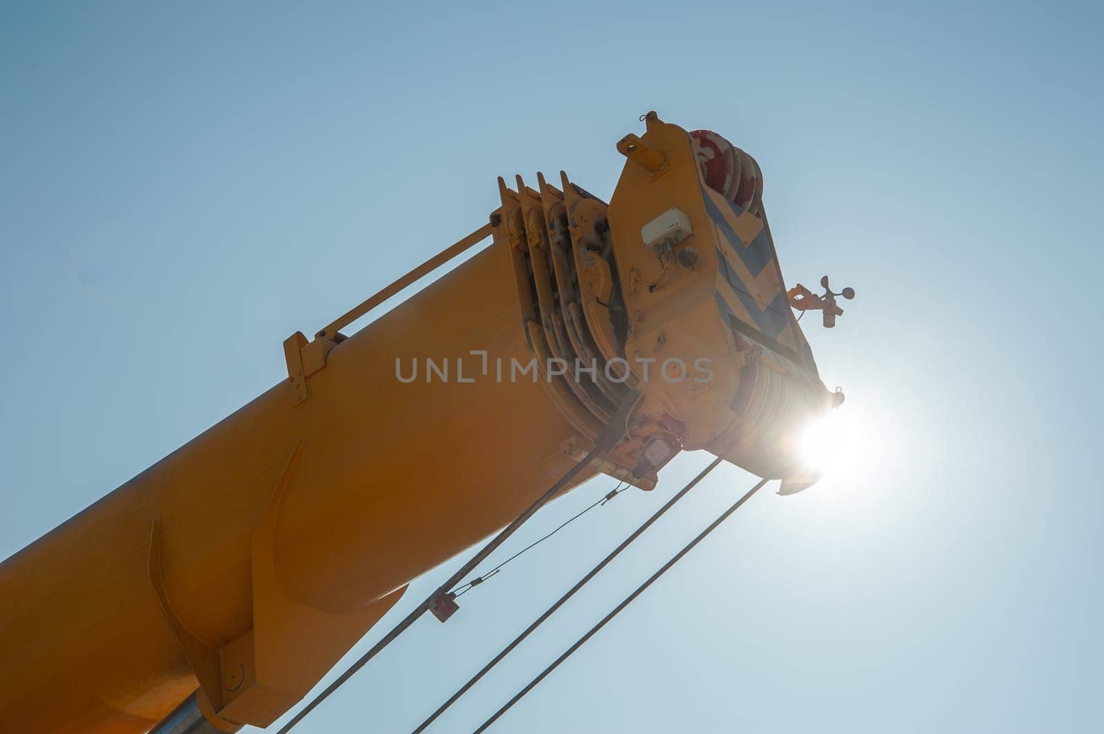 A closeup of a track crane tower against a sunny sky