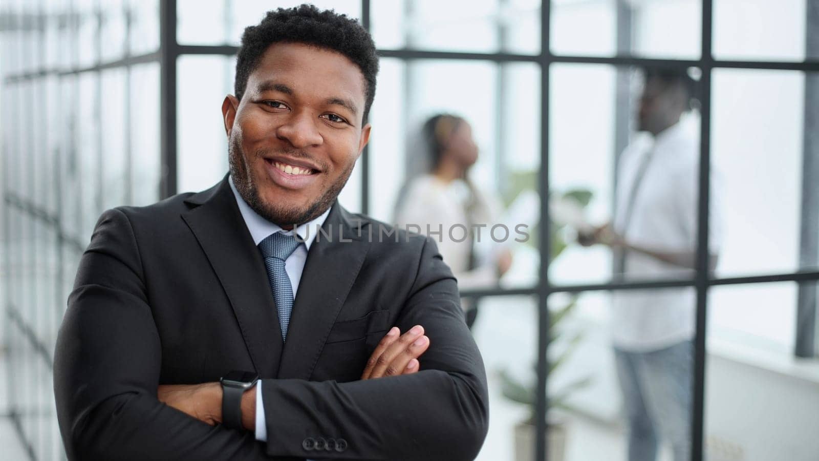 African American businessman posing for camera in front of colleagues in the background in the office