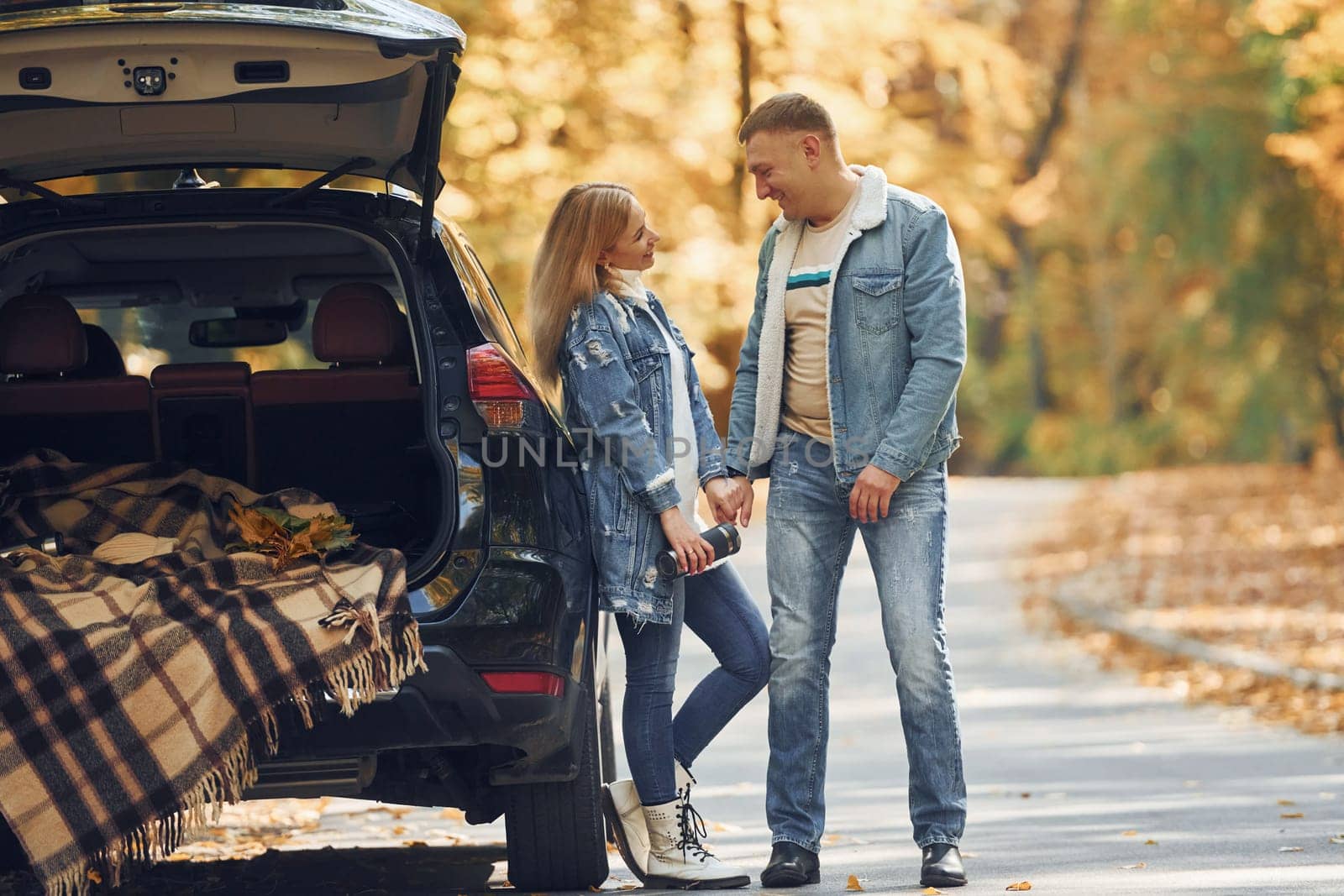 Couple standing on the road in park near automobile by Standret