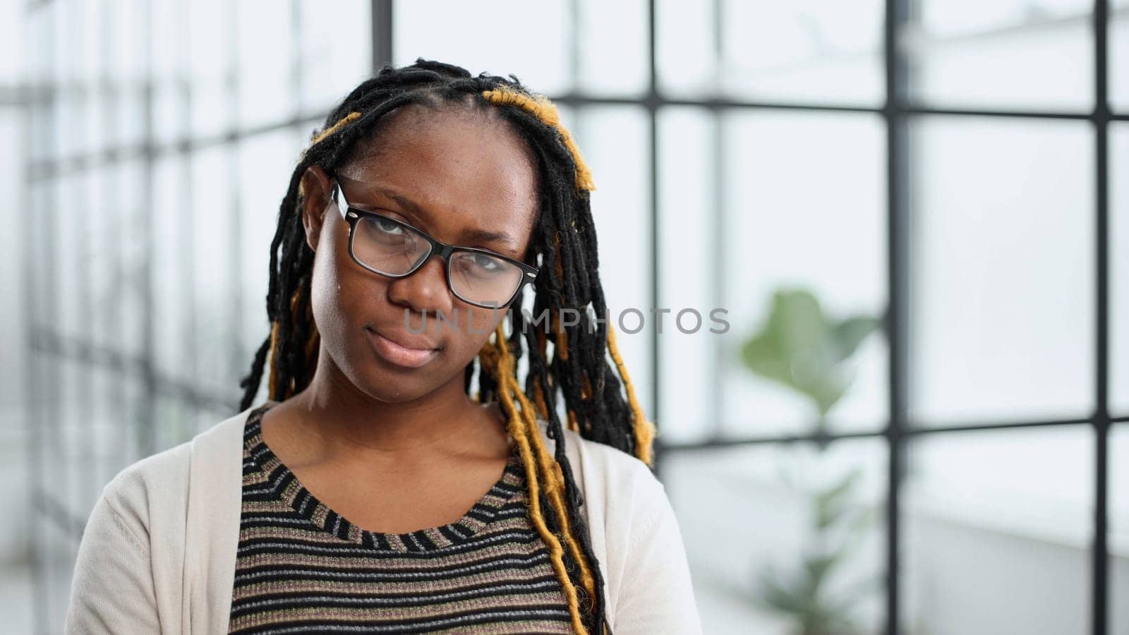 young woman in glasses standing looking at camera in modern office