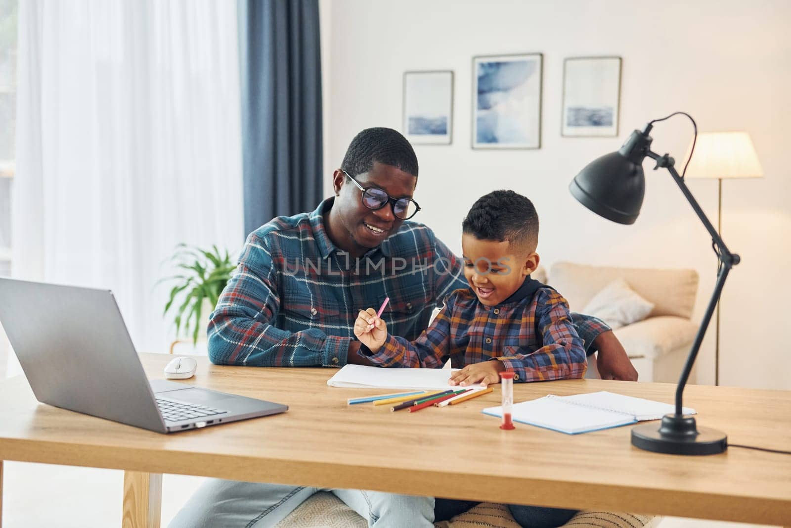 Drawing together. African american father with his young son at home.