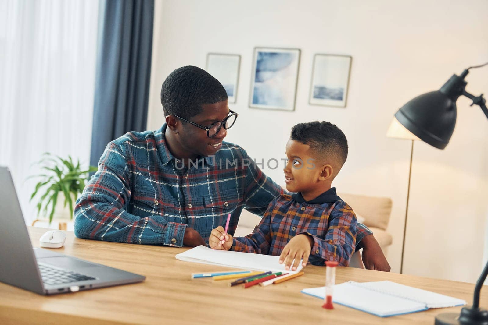 Drawing together. African american father with his young son at home.