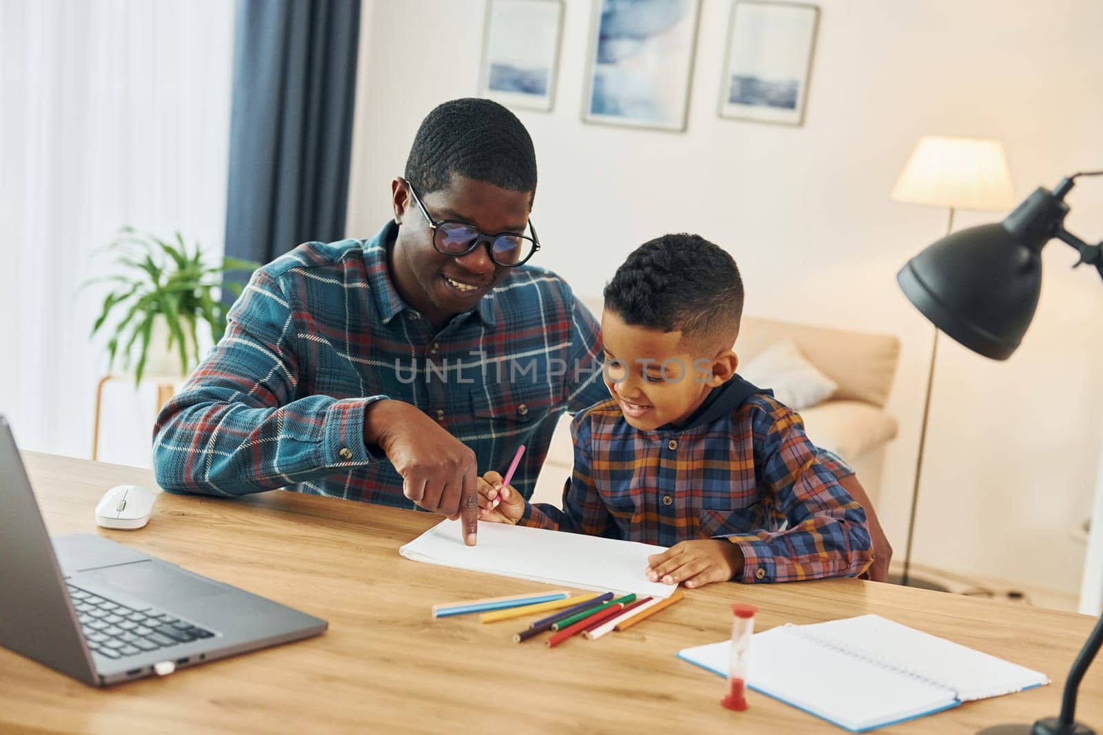 Drawing together. African american father with his young son at home.