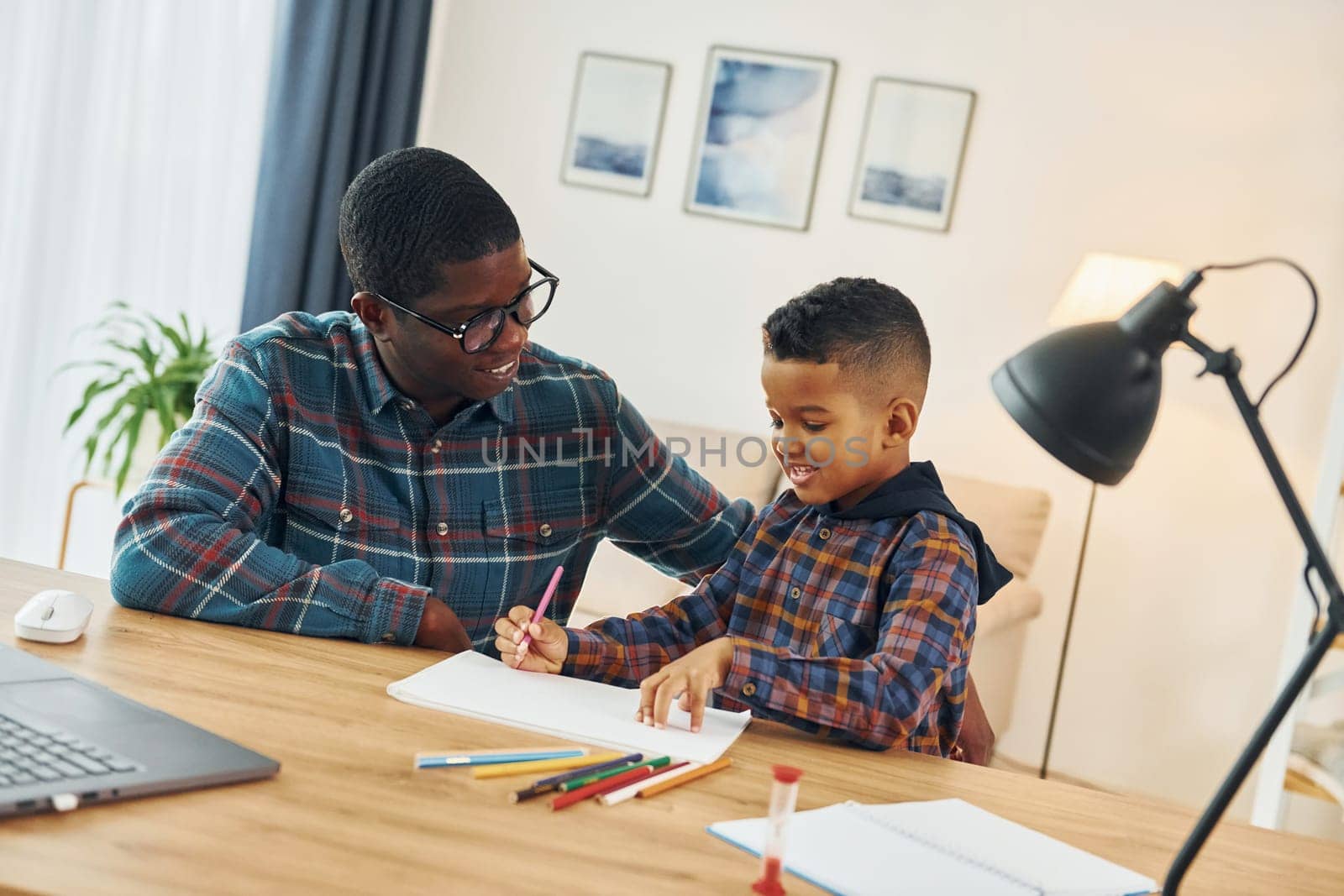 Drawing together. African american father with his young son at home.