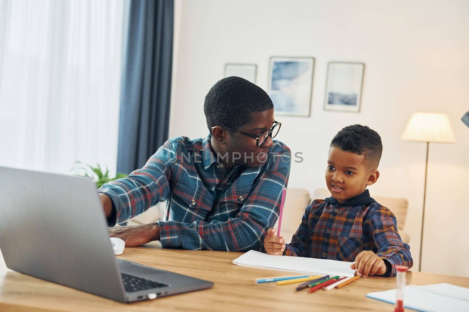 Drawing together. African american father with his young son at home.