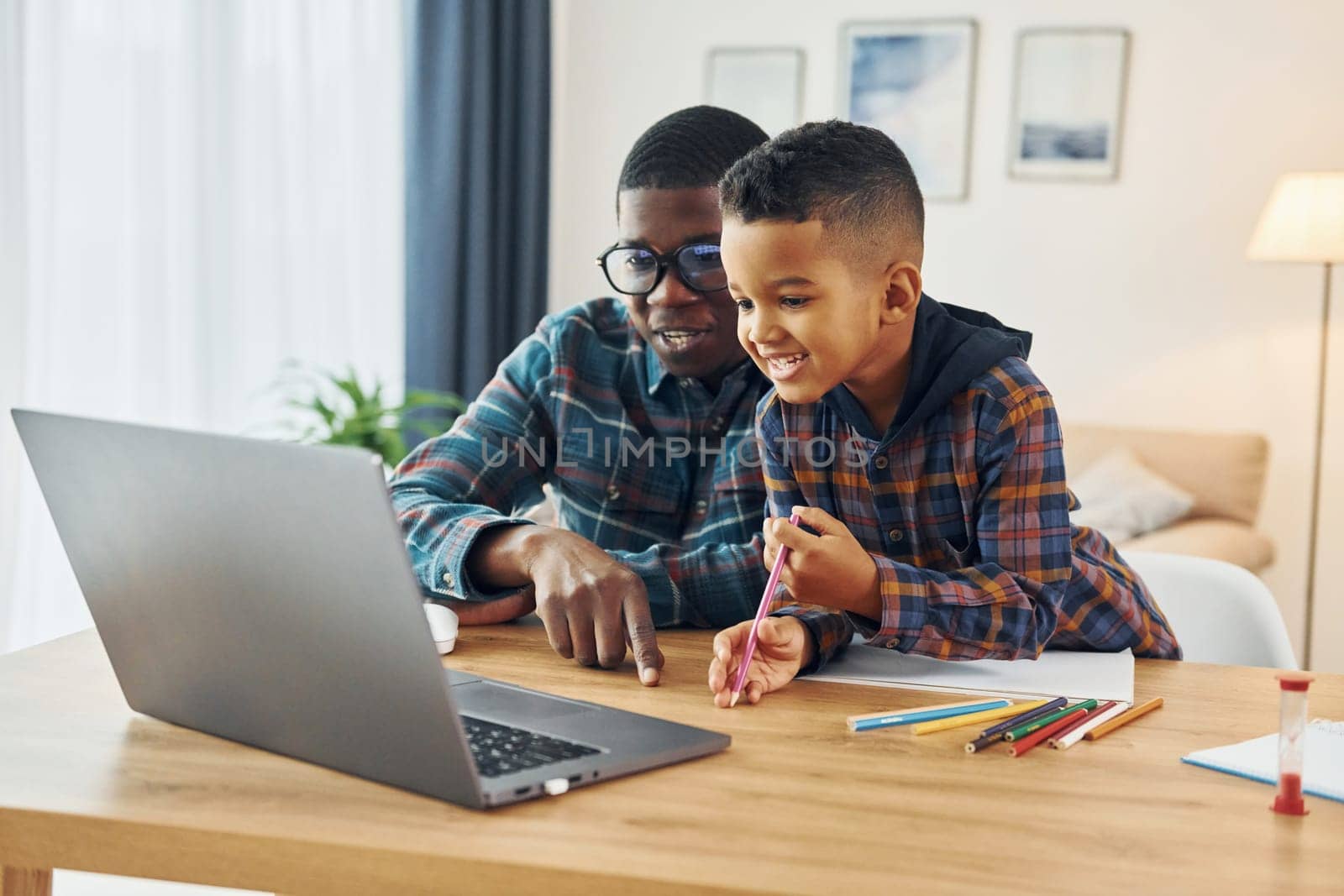 With laptop on table. African american father with his young son at home.