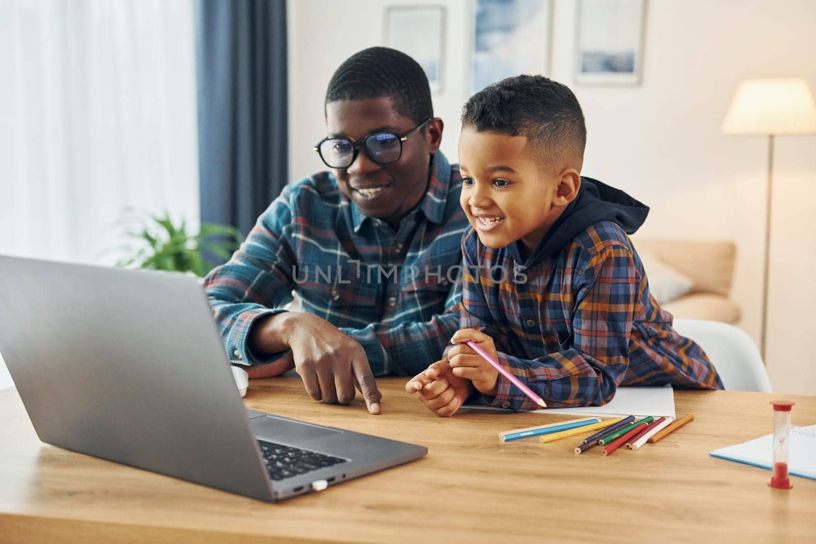 With laptop on table. African american father with his young son at home by Standret