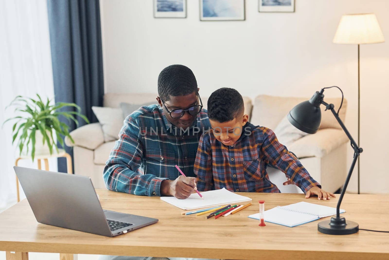 With laptop on table. African american father with his young son at home by Standret