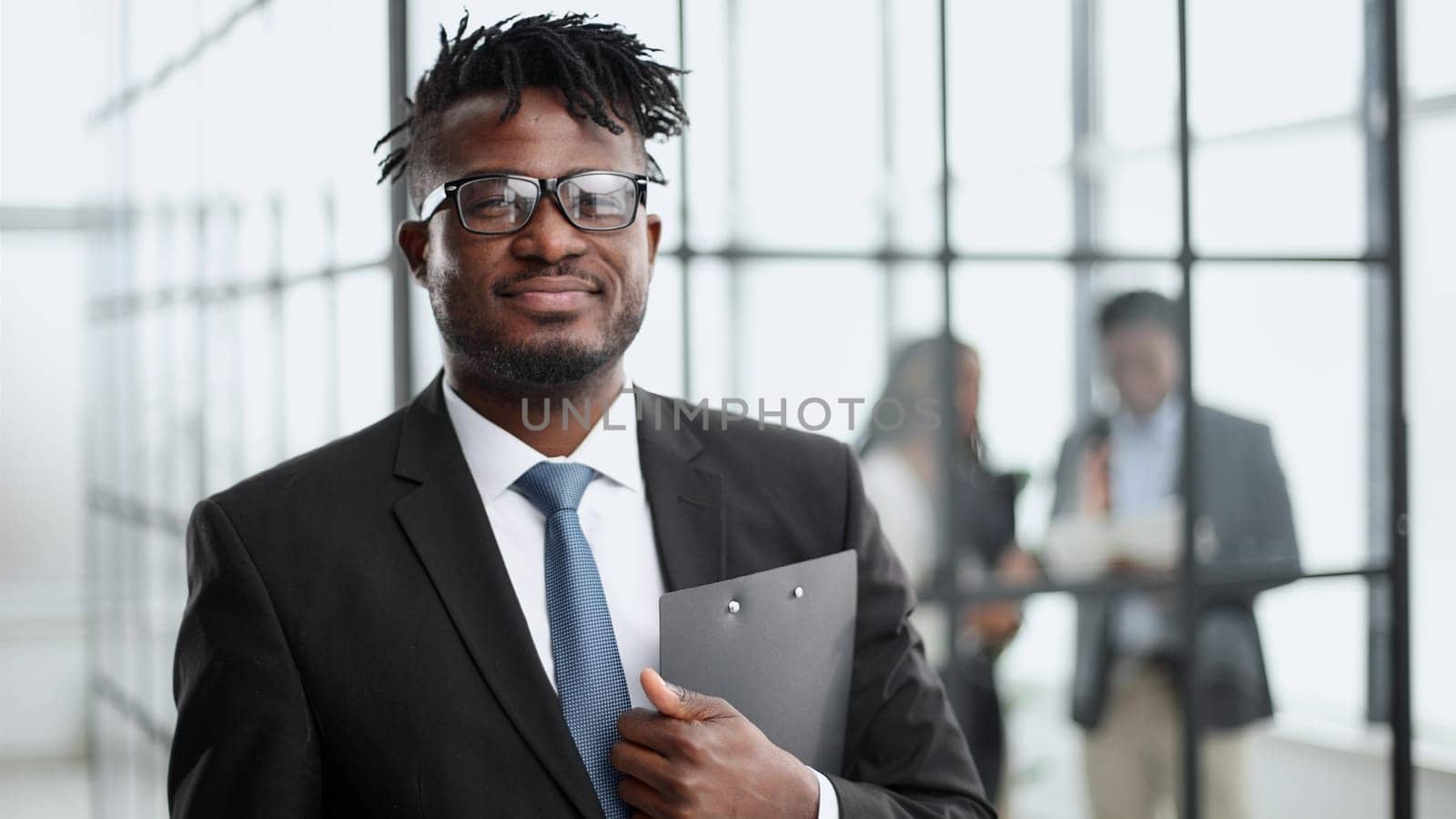 young Afro American businessman in classic suit holding folder by Prosto
