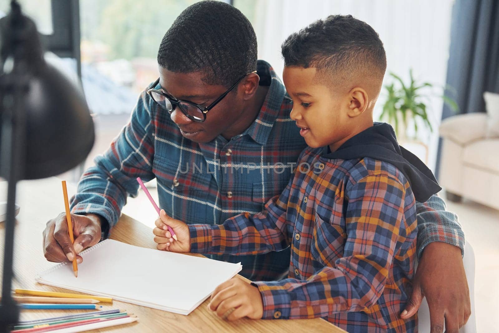 Drawing lessons. African american father with his young son at home.