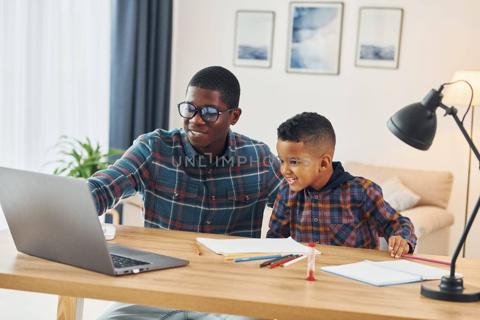 Using laptop. African american father with his young son at home.