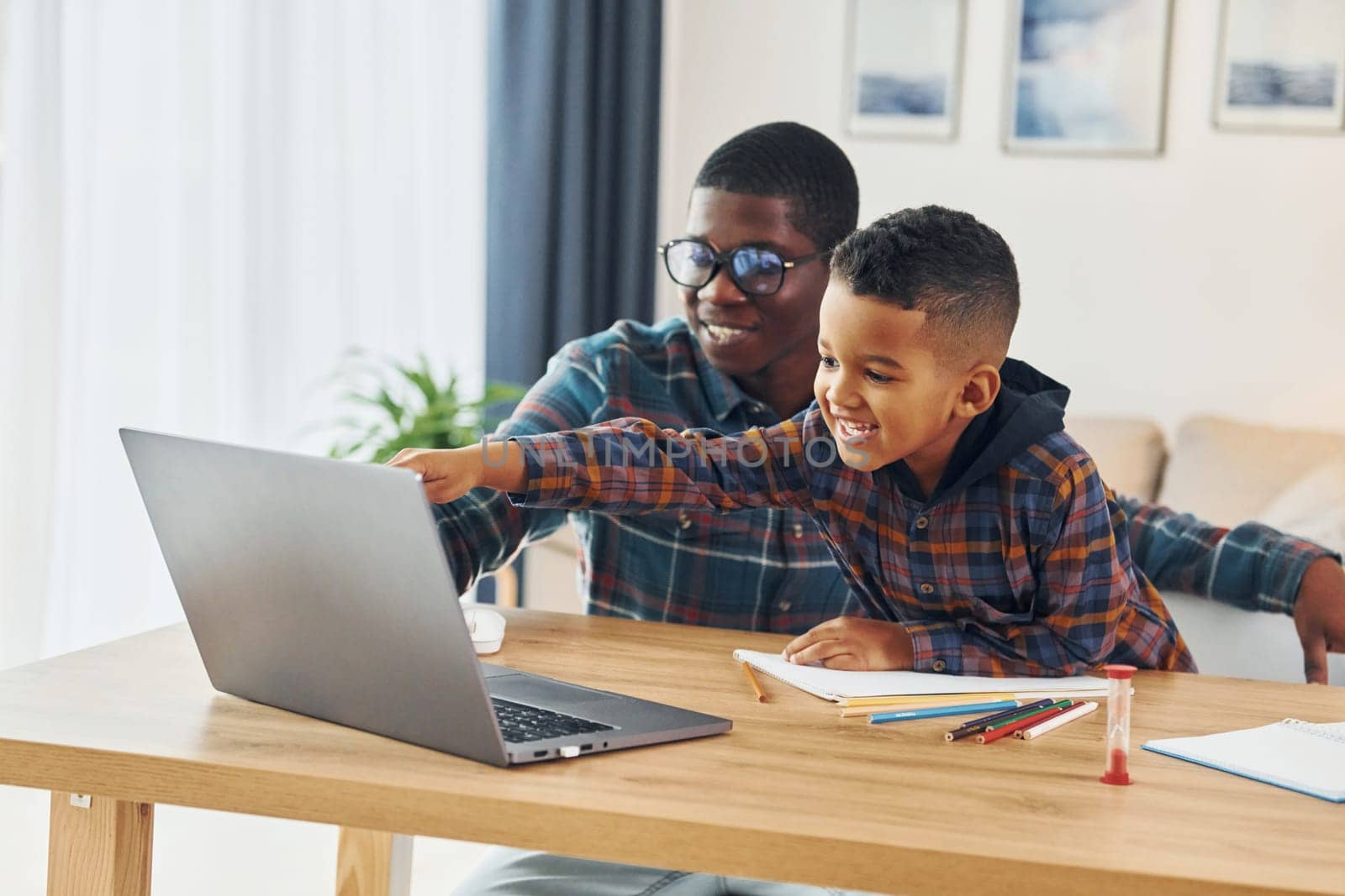 Using laptop. African american father with his young son at home by Standret