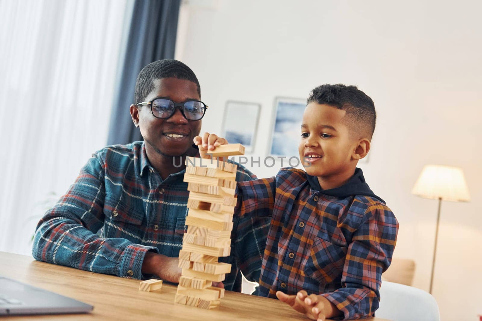 Playing bricks game. African american father with his young son at home by Standret