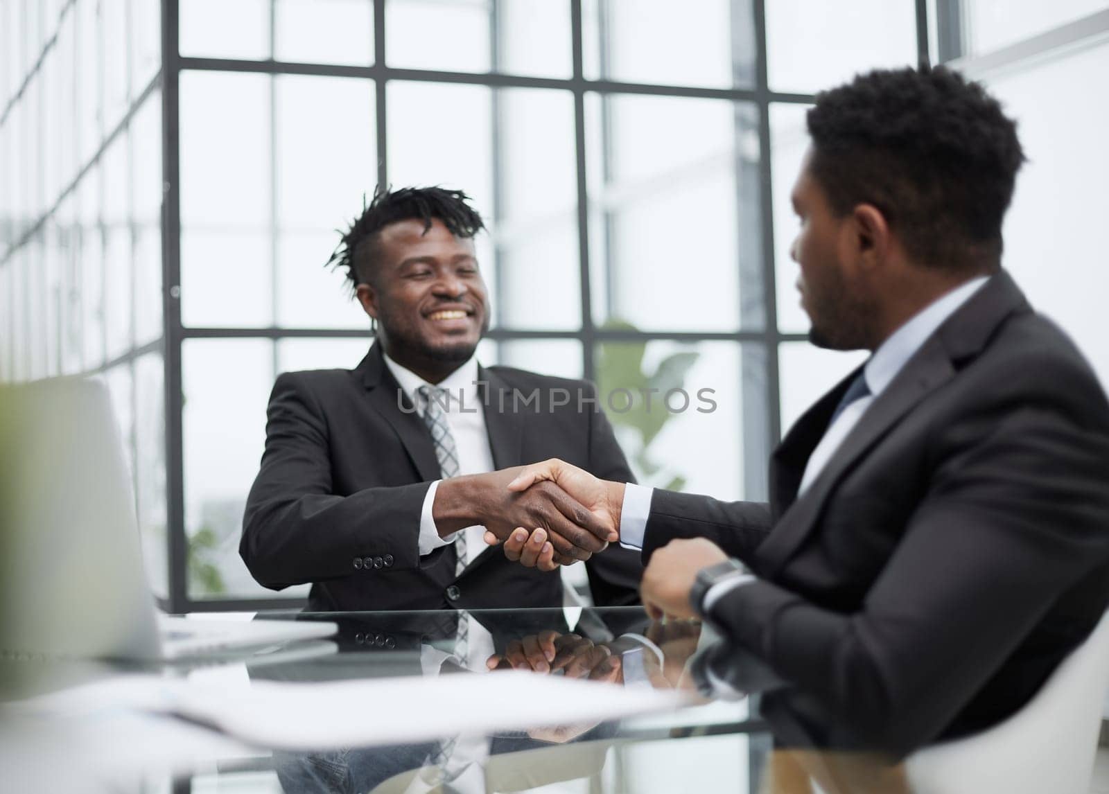 Shot of two young black men shaking hands in a modern office