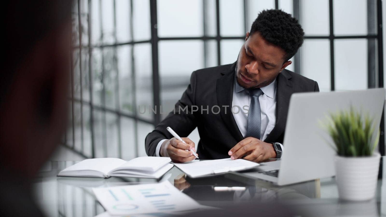 Focused young businessman signing agreement with skilled lawyer