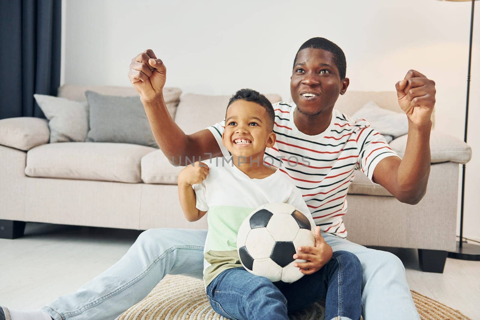 With soccer ball. African american father with his young son at home by Standret