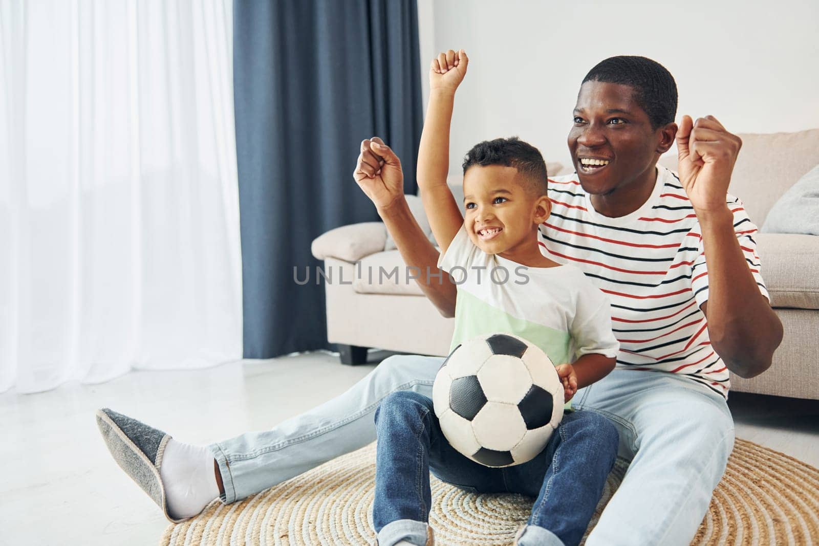 With soccer ball. African american father with his young son at home.