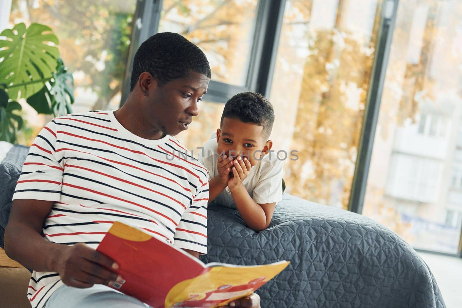 Reading book. African american father with his young son at home.