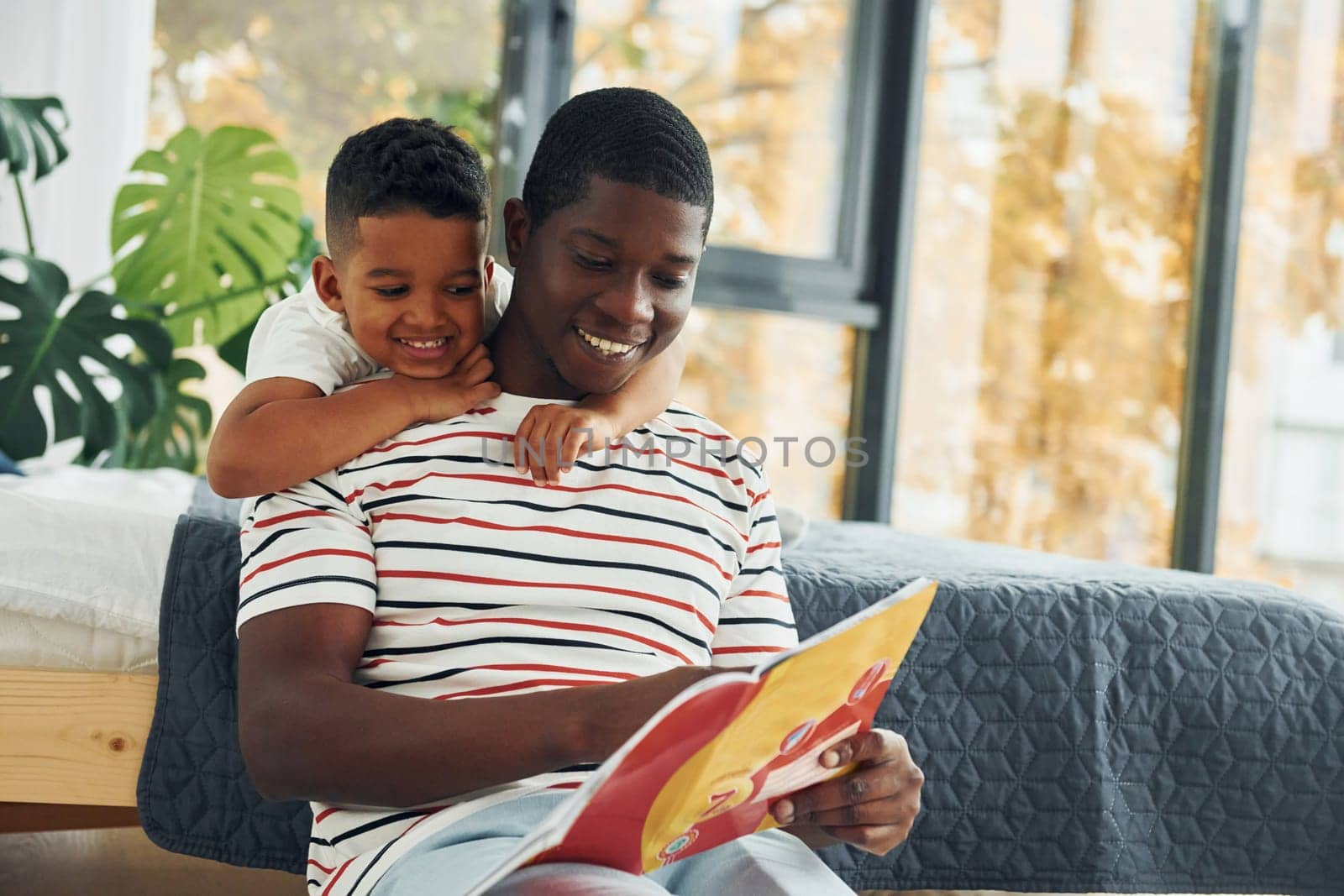 Reading book. African american father with his young son at home.