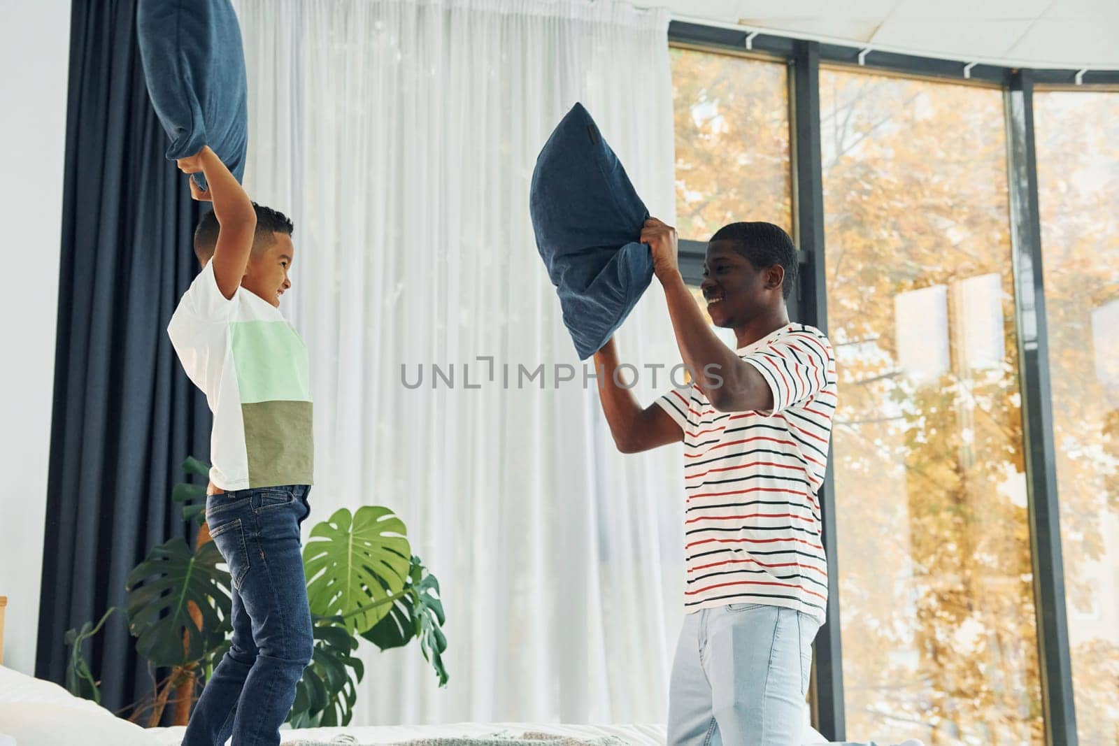 Pillow fight. African american father with his young son at home.