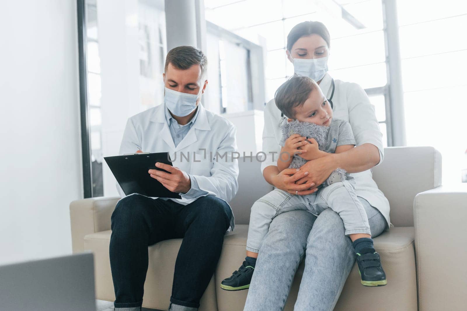 With little boy that being examined. Two doctors in white coats is in the clinic working together.