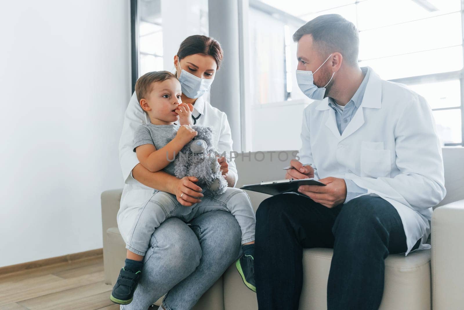 With little boy that being examined. Two doctors in white coats is in the clinic working together.