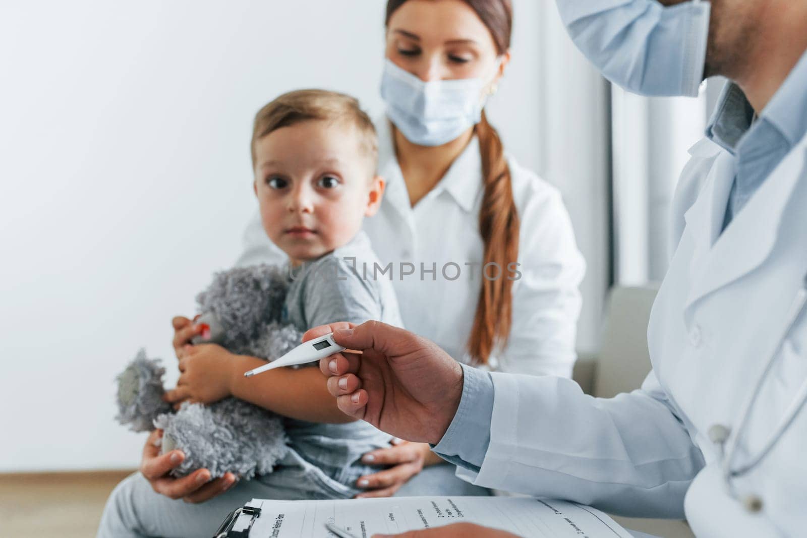 With little boy that being examined. Two doctors in white coats is in the clinic working together.