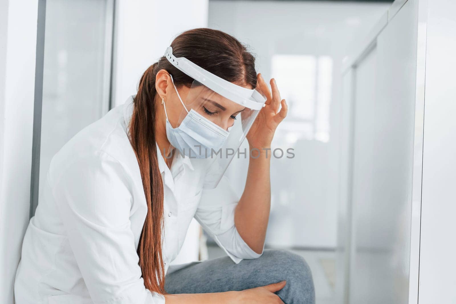 Having headache. Professional medic in white coat is in the clinic.