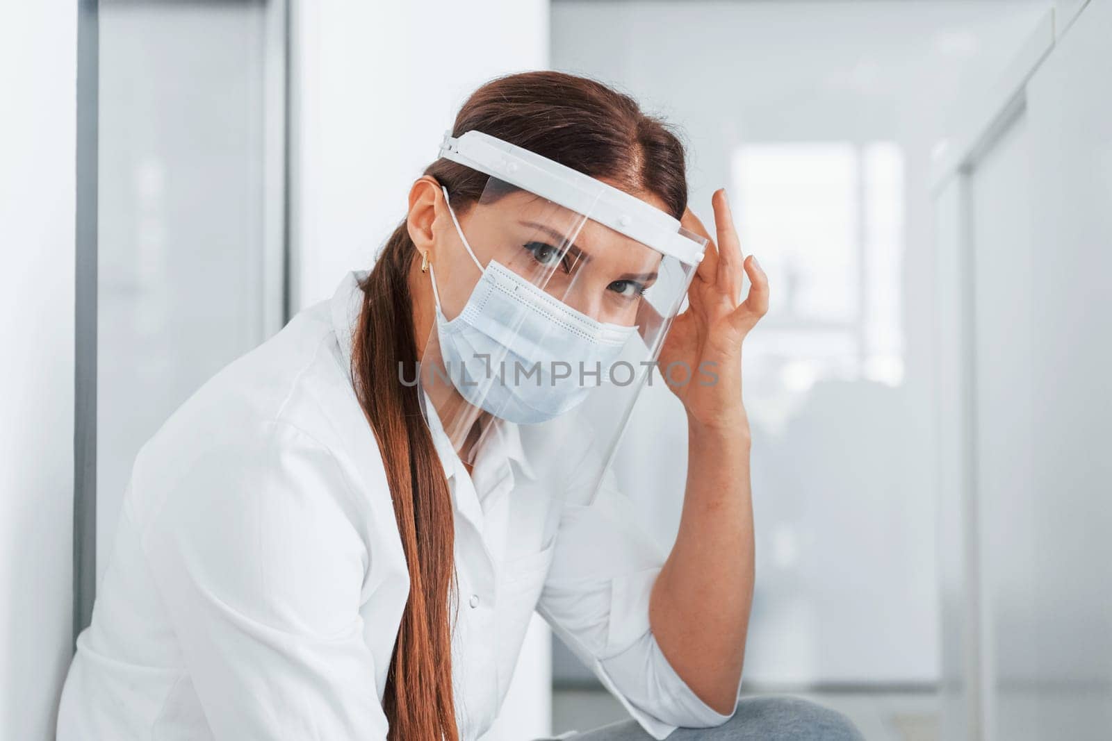 Having headache. Professional medic in white coat is in the clinic.