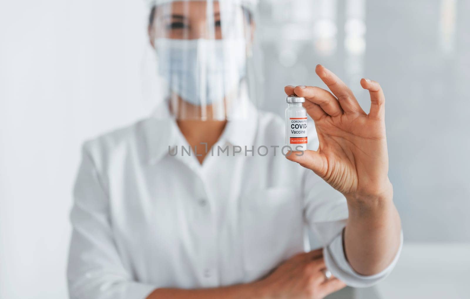 Test tube with COVID-19 vaccine in hands. Professional medic in white coat is in the clinic.