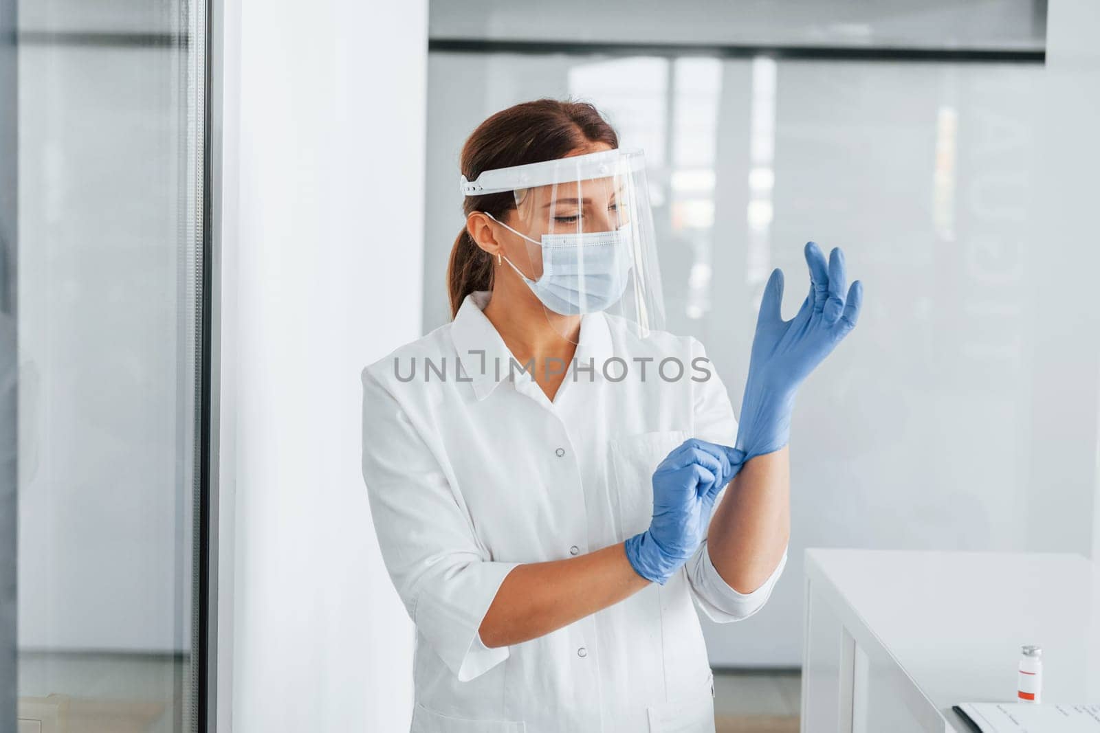 Standing indoors. Professional medic in white coat is in the clinic.