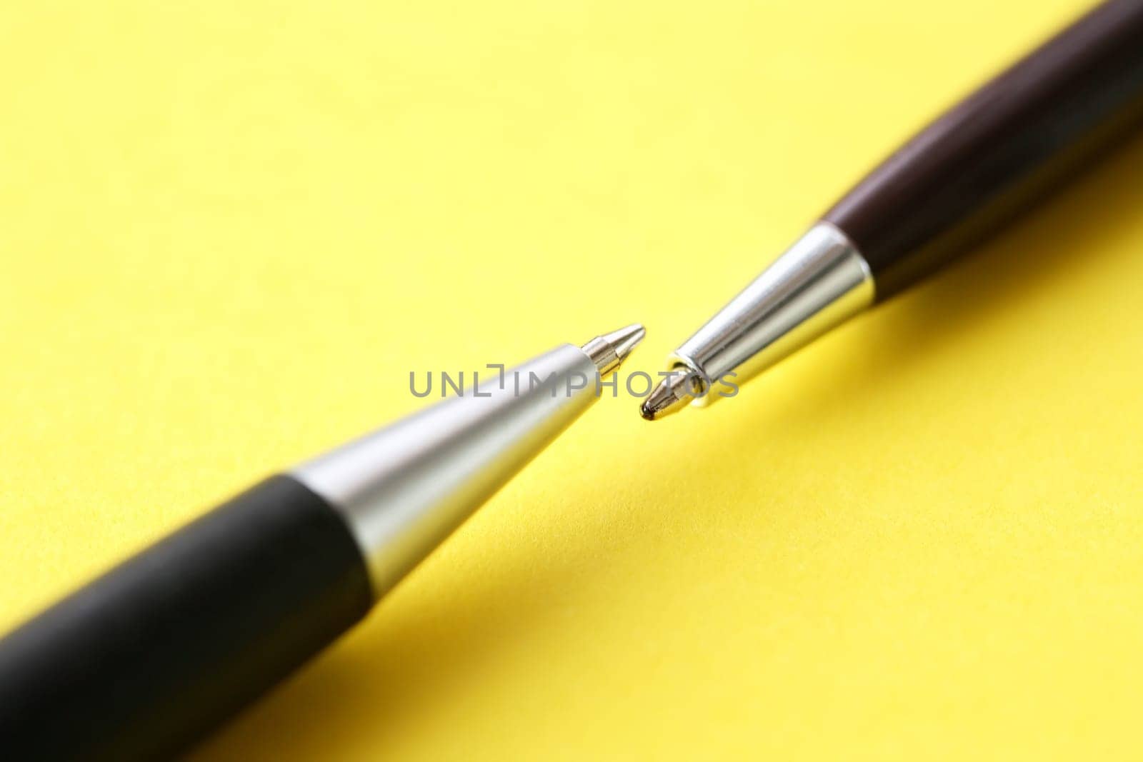 Two pens opposite each other on yellow paper background