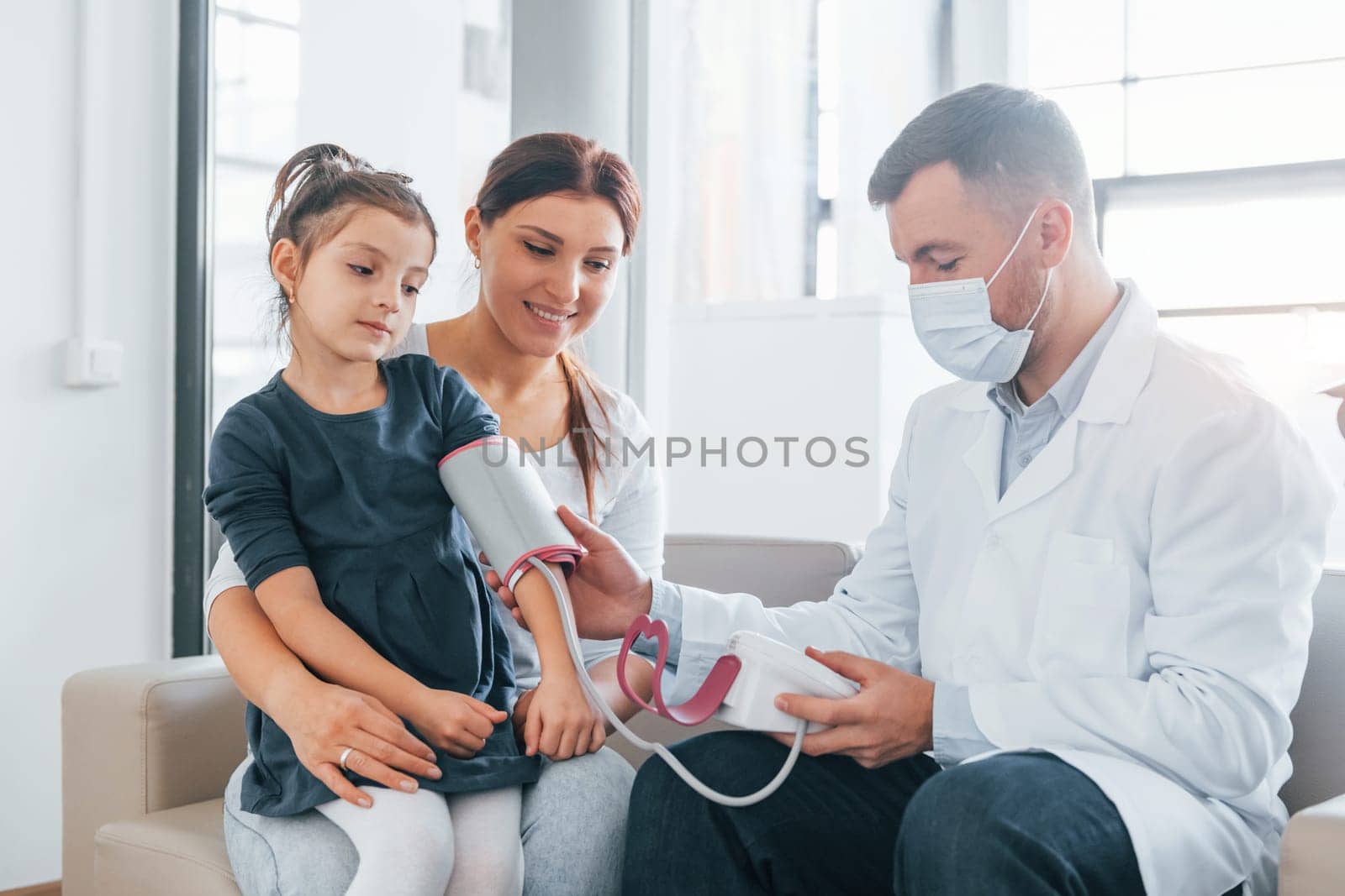 Helping kid. Two doctors in white coats is in the clinic working together.