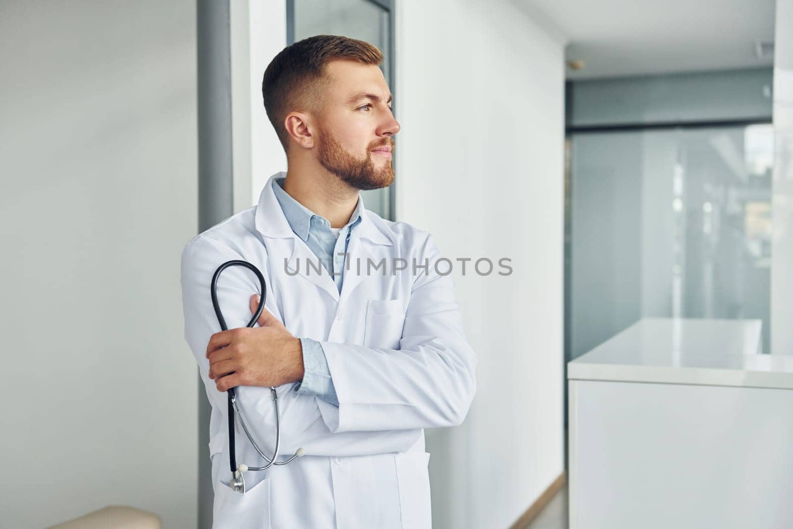 Holding stethoscope. Professional medic in white coat is in the clinic.