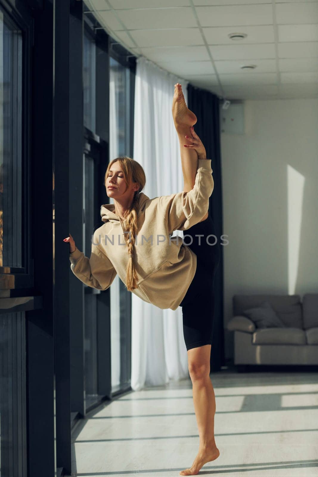 Posing for the camera. Woman in sportive clothes doing yoga indoors.