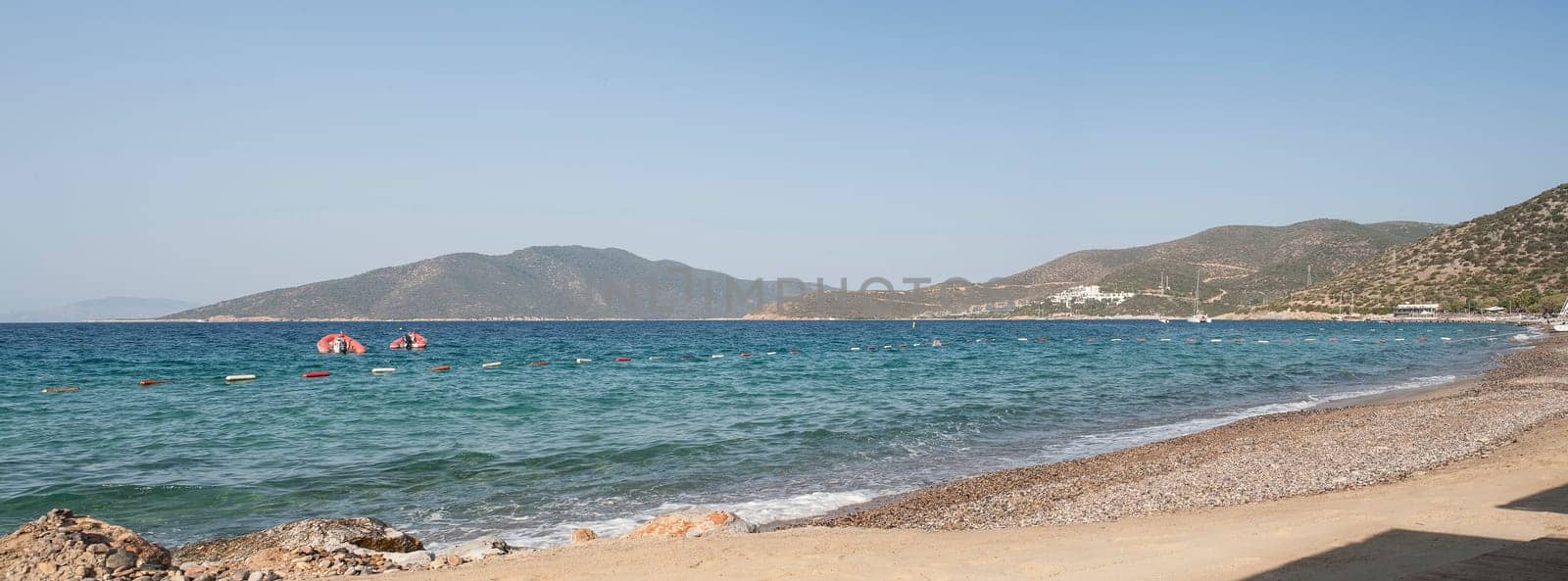 Bodrum - nice view of the sea. Beach Bodrum with sand and mountains, the sea with the ship. Beautiful harbor near the sandy beach.