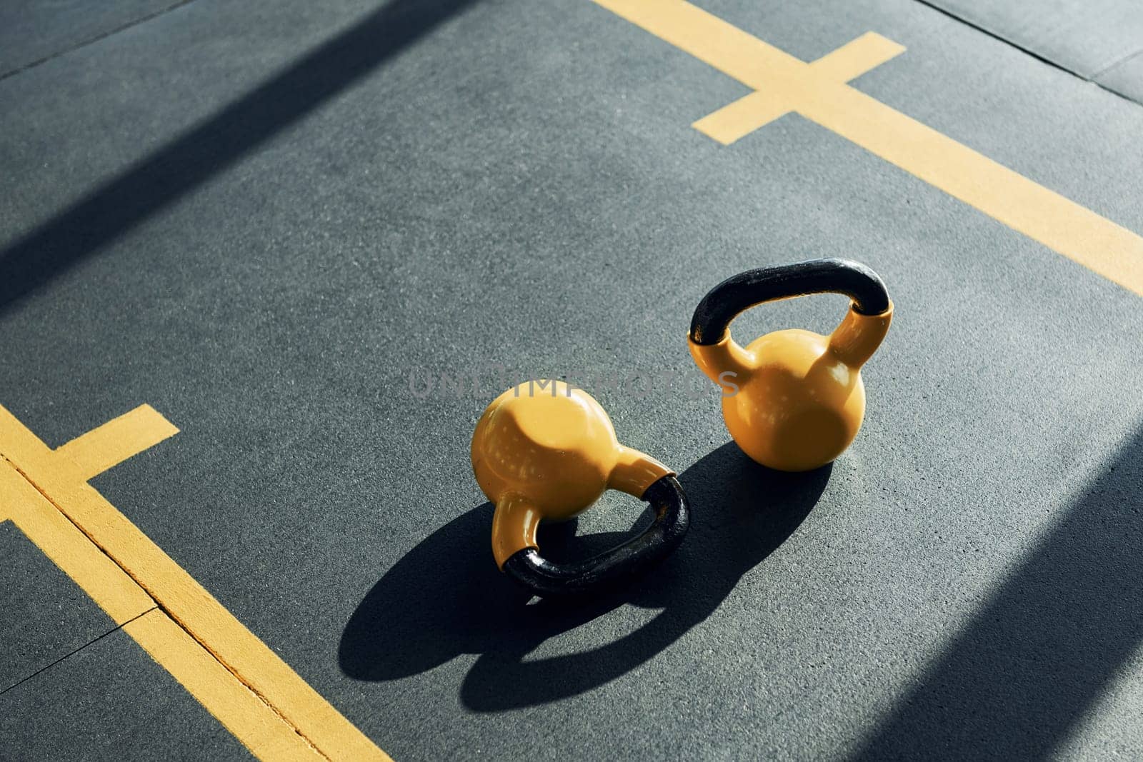 Weights painted in yellow color laying down on the ground in the gym.
