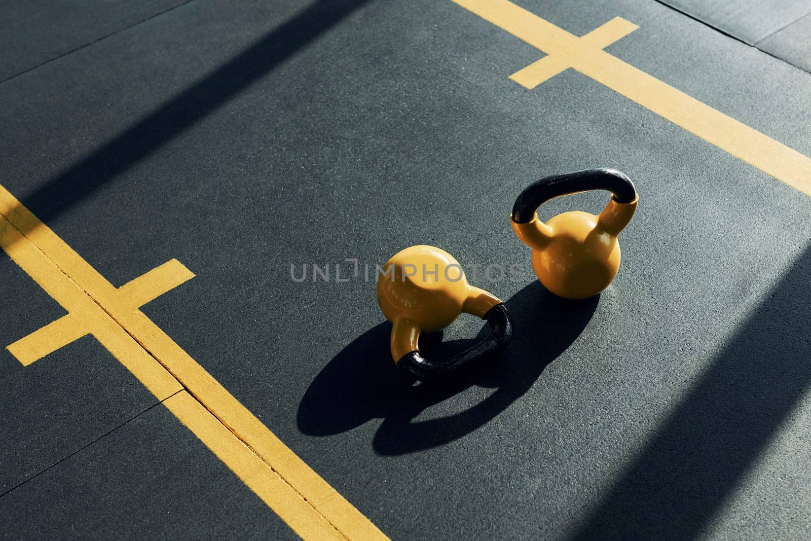 Weights painted in yellow color laying down on the ground in the gym.