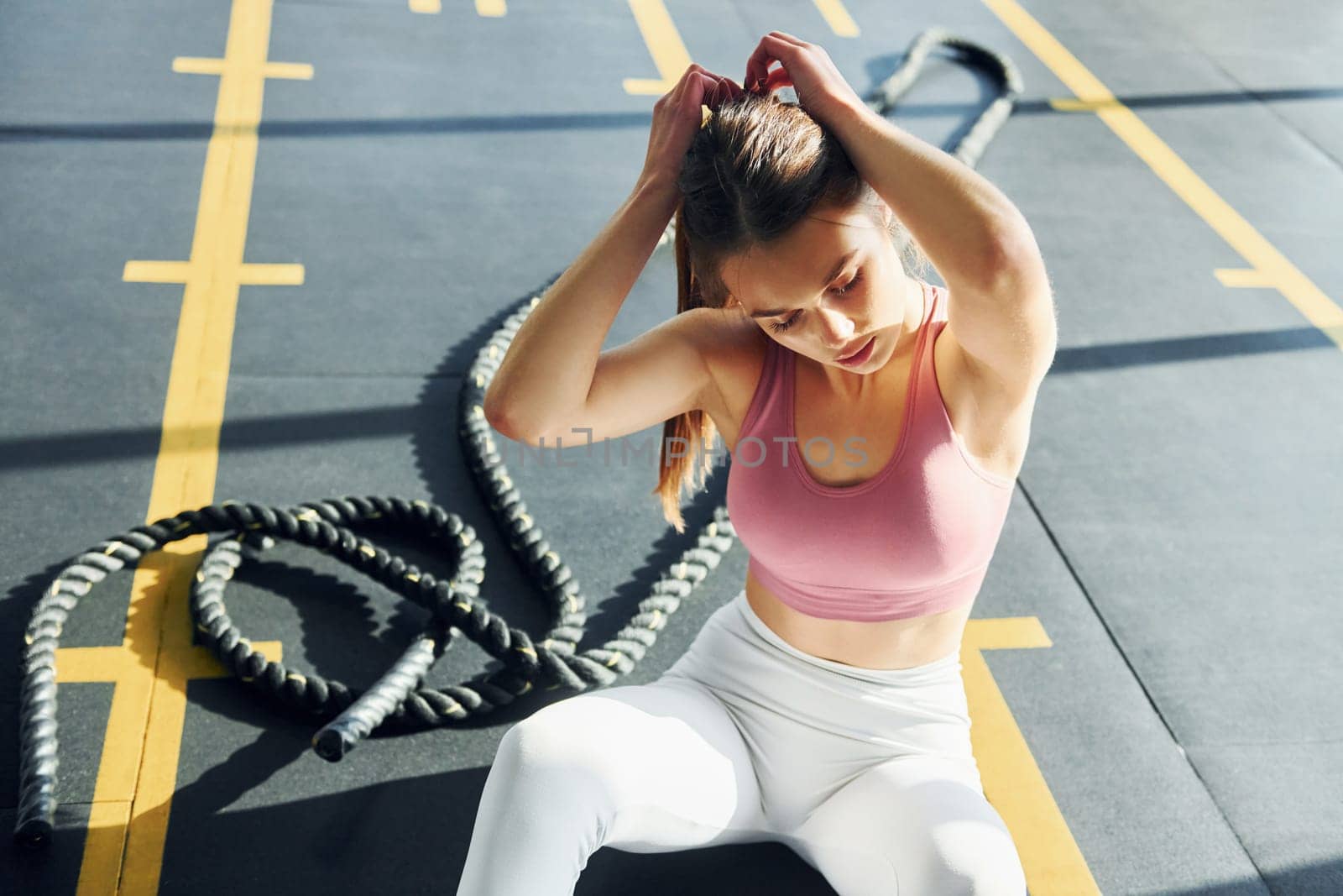 Sitting on the ground. Beautiful young woman with slim body type is in the gym.