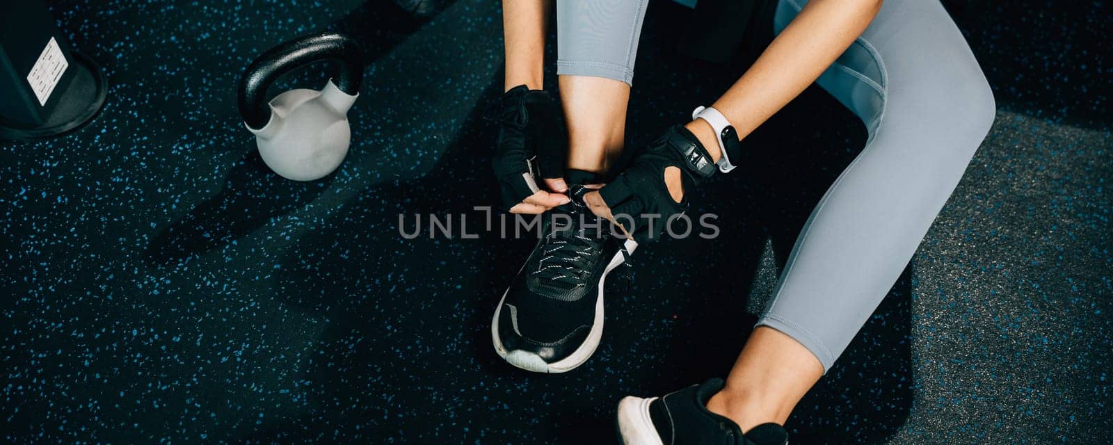 Close-up of a woman's legs as she ties her shoelaces before starting her exercise routine. The shot is perfect for fitness and health concepts.