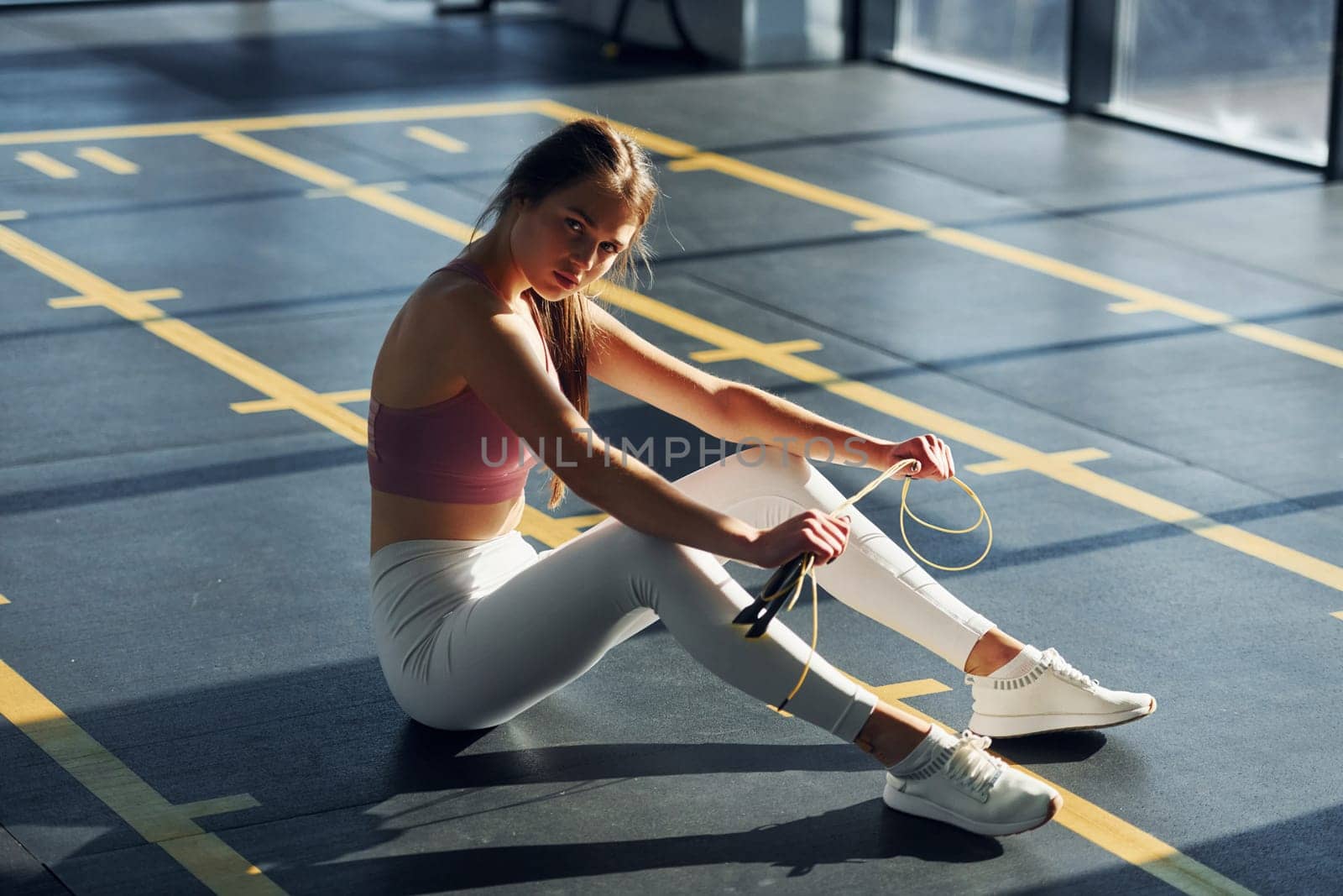 On the ground. Beautiful young woman with slim body type is in the gym.