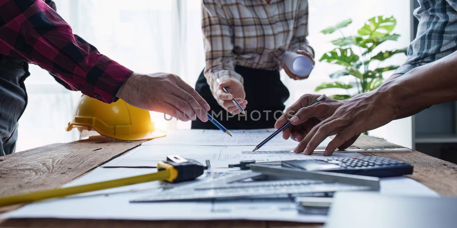 Architect and Engineer working with blueprints for architectural plan, engineer sketching a construction project, green energy concept by itchaznong