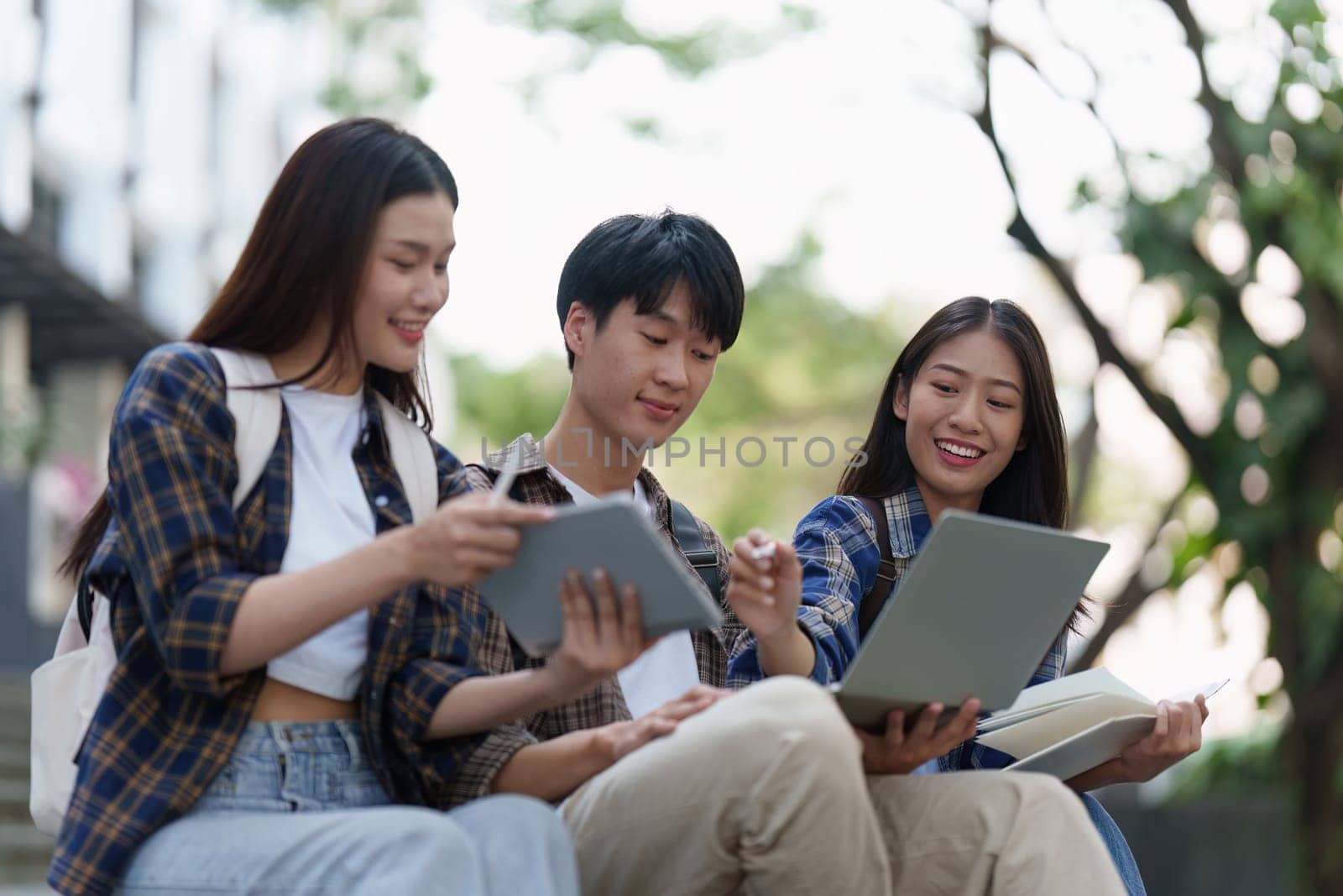 Young Asian woman college student with friends at outdoors. College student working on the college campus, education, school, study.