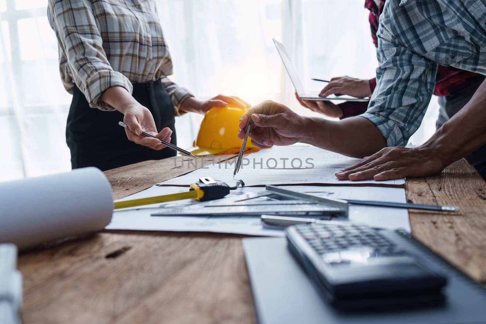 Architect and Engineer working with blueprints for architectural plan, engineer sketching a construction project, green energy concept.