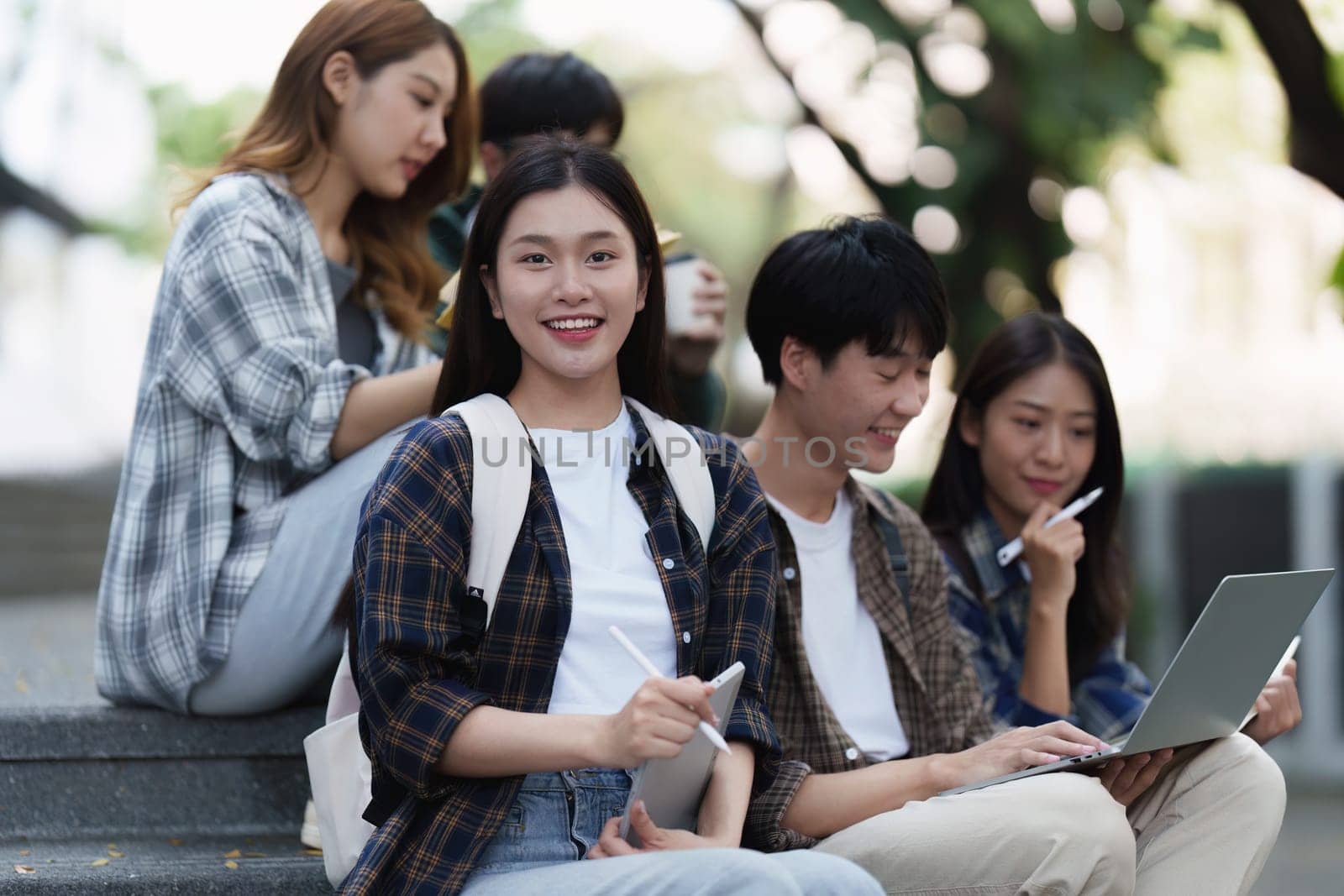 Young Asian woman college student with friends at outdoors. College student working on the college campus, education, school, study.