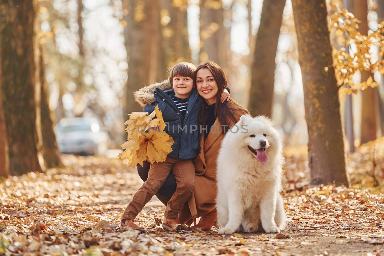 WIth cute dog. Mother with her son is having fun outdoors in the autumn forest.