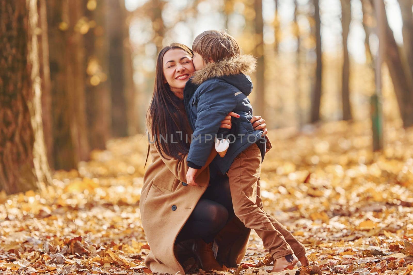Active weekend time spending. Mother with her son is having fun outdoors in the autumn forest.