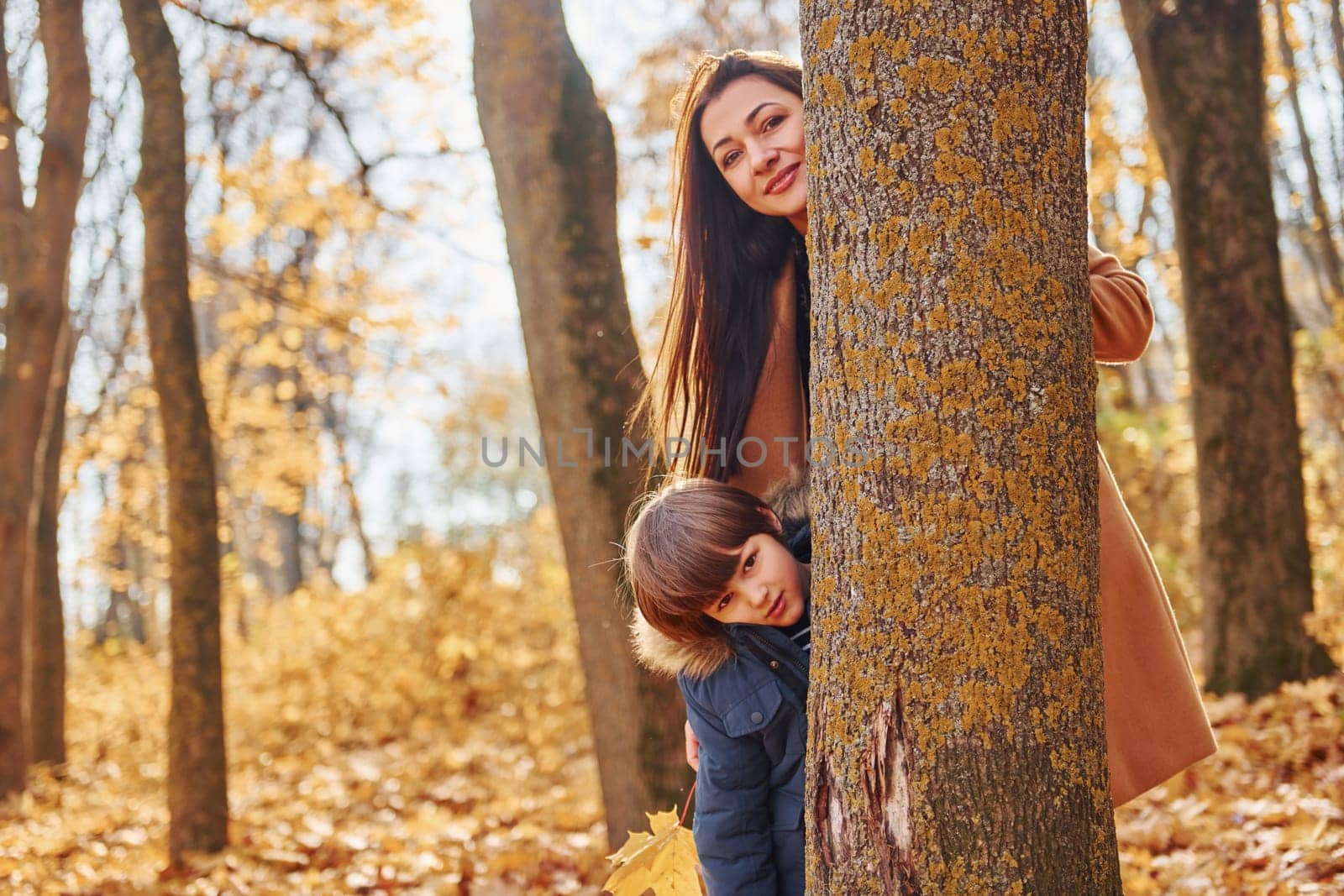 Cheerful woman and boy. Mother with her son is having fun outdoors in the autumn forest.